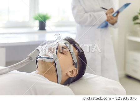Man With Oxygen Mask Under Doctor Care In Hospital 129935076
