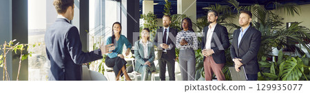 Company employees standing in a row and discussing work project in modern office. 129935077