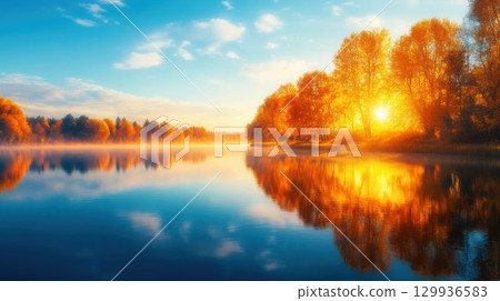 serene lake at dawn with mist rolling over still water, surrounded by vibrant autumn trees reflecting golden sunlight 129936583
