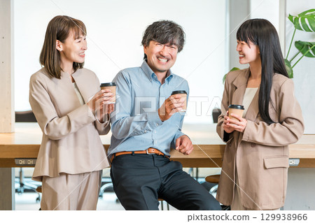 Businessman and businesswoman chatting over coffee in the office Businessman and businesswoman chatting over coffee in the office 129938966