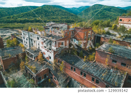 An abandoned mining and processing facility sits in disrepair, with crumbling structures overtaken by nature. An abandoned mining and processing facility sits in disrepair, with crumbling structures overtaken by nature. 129939142