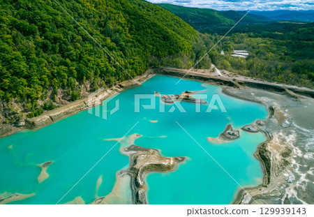 The effects of pollution on a natural habitat, featuring damaged terrain and pools of toxic water surrounded by lush hills. The effects of pollution on a natural habitat, featuring damaged terrain and pools of toxic water surrounded by lush hills. 129939143