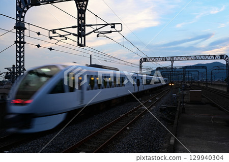 Spacia X12 departs Tochigi Station at dusk and accelerates. 129940304