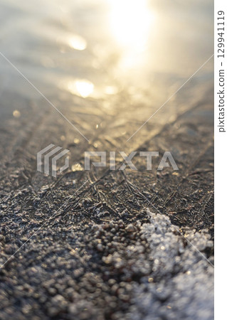 冰凍的水坑在清晨的陽光下閃閃發光 129941119