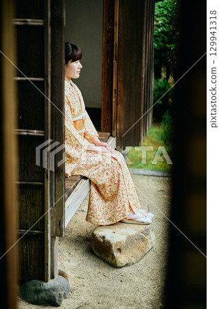 A woman in a kimono quietly standing on the veranda 129941318