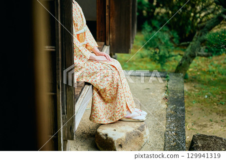 A woman in a kimono quietly standing on the veranda 129941319