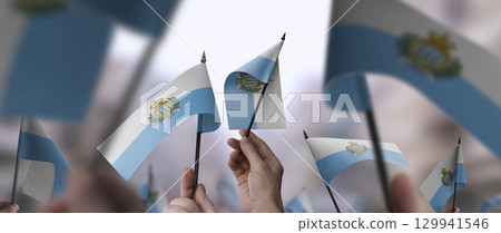 San Marino flags in their hands on a blurred urban background 129941546