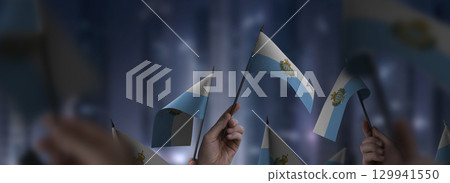 San Marino flags in their hands on a blurred urban background 129941550