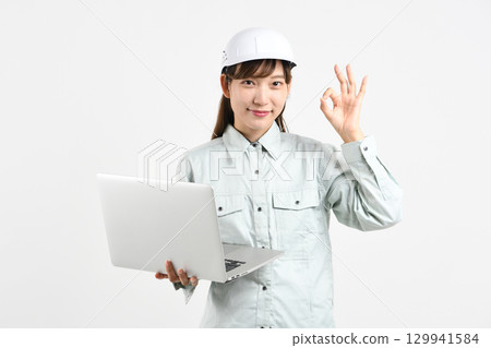 Image of an Asian woman in work clothes holding a PC and making an OK sign 129941584