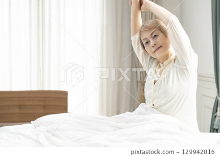 Senior woman stretching in bed 129942016