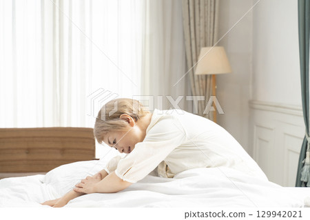 Senior woman stretching in bed Senior woman stretching in bed 129942021