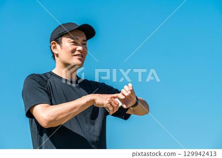 一位身穿運動服的中年男子使用智慧手錶、計步器和步數計數器來管理自己的健康和保健 129942413