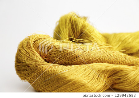 Gold thread photographed against a white background and slightly reddish gold thread 129942688