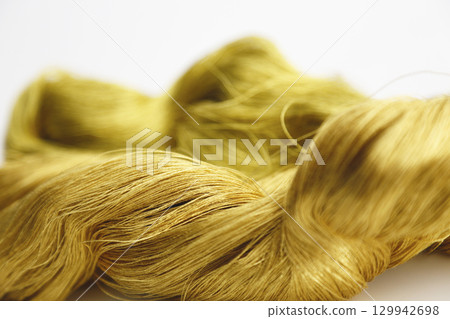 Gold thread photographed against a white background and slightly reddish gold thread Gold thread photographed against a white background and slightly reddish gold thread 129942698