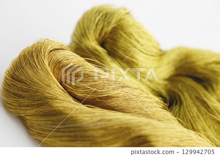 Gold thread photographed against a white background and slightly reddish gold thread Gold thread photographed against a white background and slightly reddish gold thread 129942705