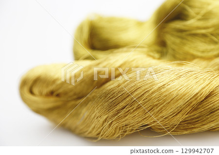 Gold thread photographed against a white background and slightly reddish gold thread Gold thread photographed against a white background and slightly reddish gold thread 129942707