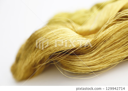 Gold thread photographed against a white background and slightly reddish gold thread Gold thread photographed against a white background and slightly reddish gold thread 129942714