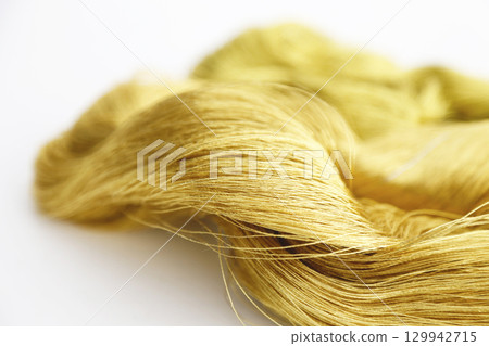 Gold thread photographed against a white background and slightly reddish gold thread Gold thread photographed against a white background and slightly reddish gold thread 129942715
