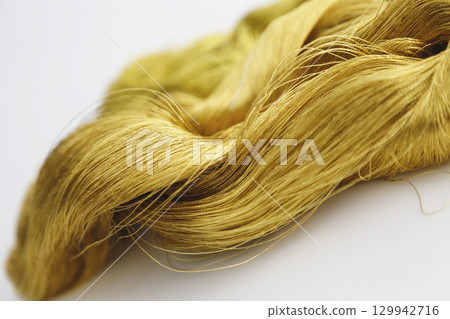 Gold thread photographed against a white background and slightly reddish gold thread 129942716