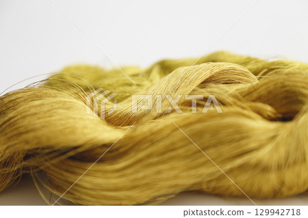 Gold thread photographed against a white background and slightly reddish gold thread Gold thread photographed against a white background and slightly reddish gold thread 129942718