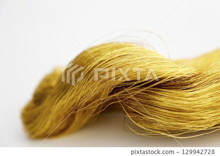 Gold thread photographed against a white background and slightly reddish gold thread Gold thread photographed against a white background and slightly reddish gold thread 129942728