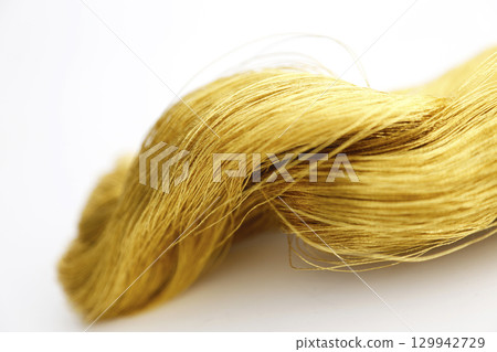Gold thread photographed against a white background and slightly reddish gold thread Gold thread photographed against a white background and slightly reddish gold thread 129942729