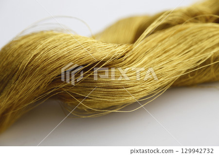 Gold thread photographed against a white background and slightly reddish gold thread Gold thread photographed against a white background and slightly reddish gold thread 129942732
