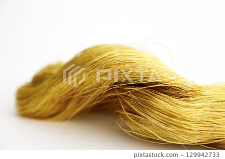 Gold thread photographed against a white background and slightly reddish gold thread Gold thread photographed against a white background and slightly reddish gold thread 129942733