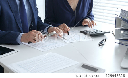 Chartered accountants analyzing financial reports with a magnifying glass and calculator for precise compliance verification. Audit and taxes in business 129942828