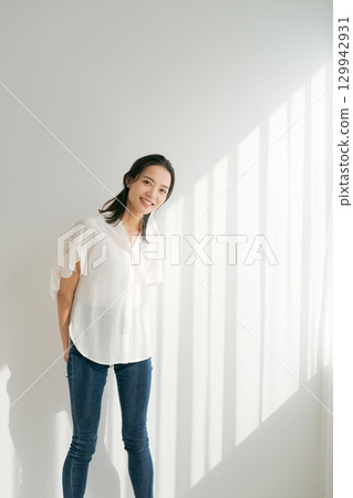 穿著牛仔布的女人站在窗邊（垂直） 129942931