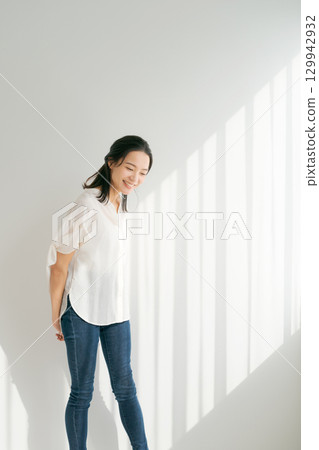 穿著牛仔布的女人站在窗邊（垂直） 129942932