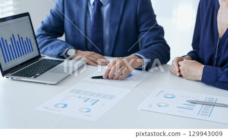 Business partners are discussing company performance and making plans based on charts and graphs displayed on laptop and printed documents. Businesspeople and finance Business partners are discussing company performance and making plans based on charts and graphs displayed on laptop and printed documents. Businesspeople and finance 129943009