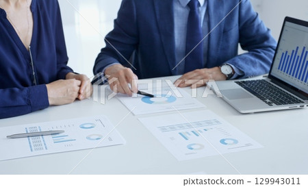 Business partners are discussing company performance and making plans based on charts and graphs displayed on laptop and printed documents. Businesspeople and finance Business partners are discussing company performance and making plans based on charts and graphs displayed on laptop and printed documents. Businesspeople and finance 129943011