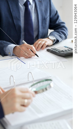 Professional male accountant calculating taxes and analyzing financial data in office setting. Audit and taxes in business 129943064