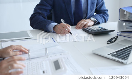 Close up of female accountant hands using calculator while collaborating with male colleague in office, calculating taxes and analyzing financial data. Audit and taxes in business Close up of female accountant hands using calculator while collaborating with male colleague in office, calculating taxes and analyzing financial data. Audit and taxes in business 129943094