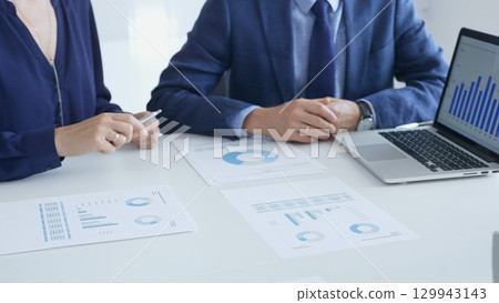 Business auditors reviewing financial data, pointing at laptop charts and discussing documents during collaborative strategy session. Business people and finance Business auditors reviewing financial data, pointing at laptop charts and discussing documents during collaborative strategy session. Business people and finance 129943143
