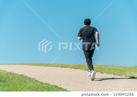A man running/jogging under a blue sky (athlete/aerobic exercise/workout/fitness) 129943288