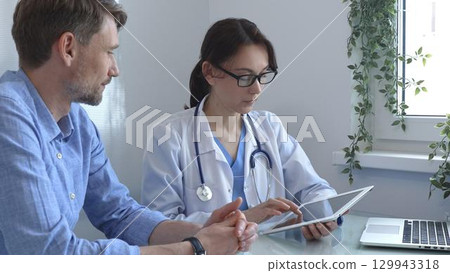 Female doctor using a digital tablet for explaining test results to a male patient during a consultation in a bright, modern medical office. Medicine concept Female doctor using a digital tablet for explaining test results to a male patient during a consultation in a bright, modern medical office. Medicine concept 129943318