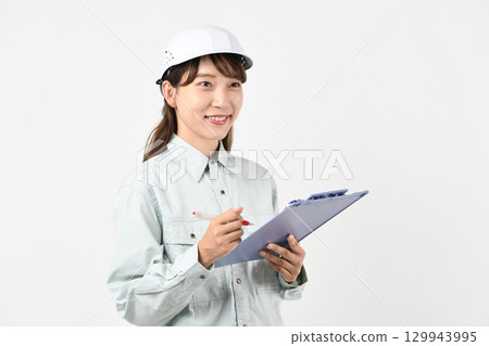 A young Asian woman in work clothes holding a board 129943995