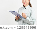 A young Asian woman in work clothes holding a board 129943996
