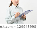 A young Asian woman in work clothes holding a board 129943998
