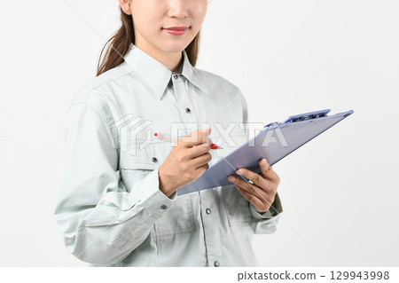 A young Asian woman in work clothes holding a board 129943998