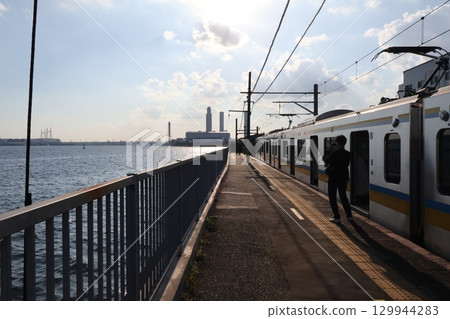 A train stopping at Umi-Shibaura Station and a factory scene in Tokyo Bay 129944283