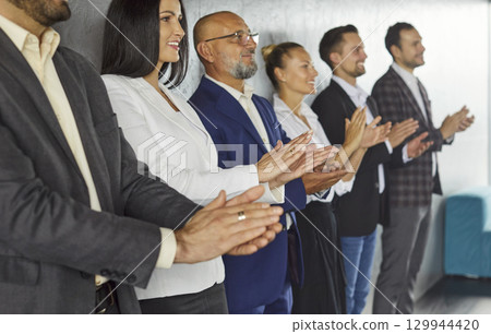 Applause of professional staff group standing by office wall on meeting, business presentation Applause of professional staff group standing by office wall on meeting, business presentation 129944420