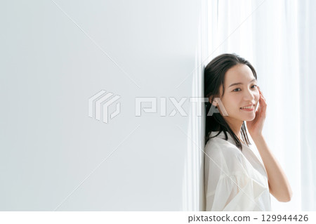 Woman in shirt standing by the window 129944426