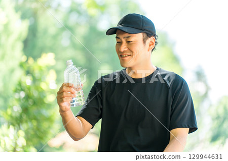 A man drinking water/mineral water during exercise (hydration, exercise, workout, running, walking) 129944631