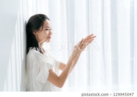 Woman massaging her hands by the window 129945047
