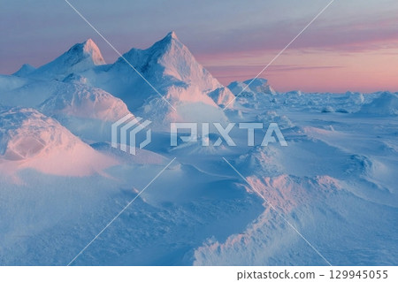 Winter arctic landscape. View of snow and ice at sunset. Ice hummocks on the frozen sea in the Arctic. Cold frosty winter weather. Harsh polar climate. Travel and hikes to the far north to the Arctic. 129945055