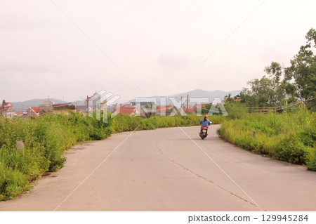 rural road in vietnam with people riding bicycles and motorbikes 129945284
