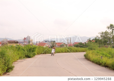 rural road in vietnam with people riding bicycles and motorbikes 129945288